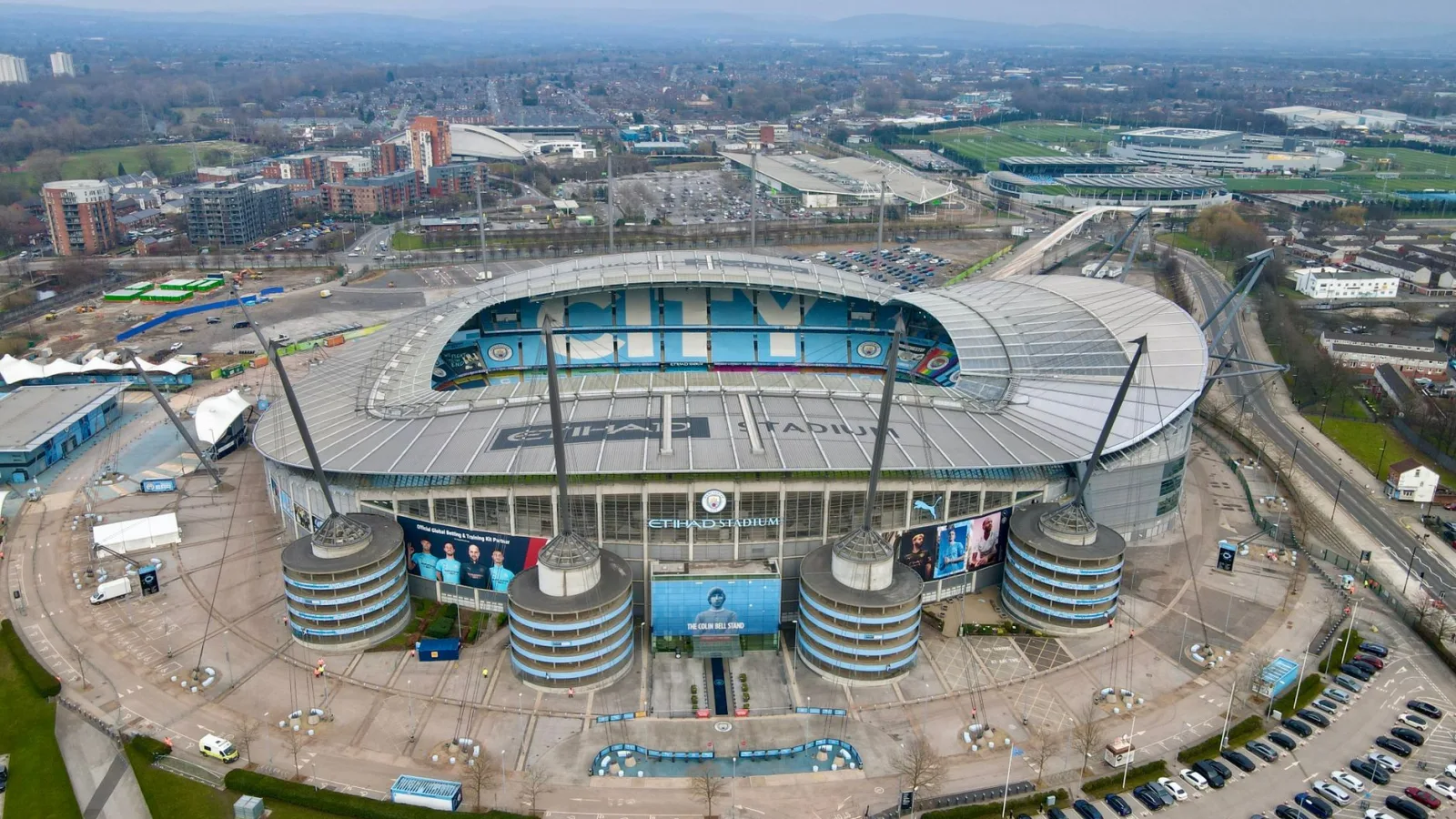 High-angle view of the iconic Etihad Stadium in Manchester, England, showcasing its modern architecture and surrounding cityscape.