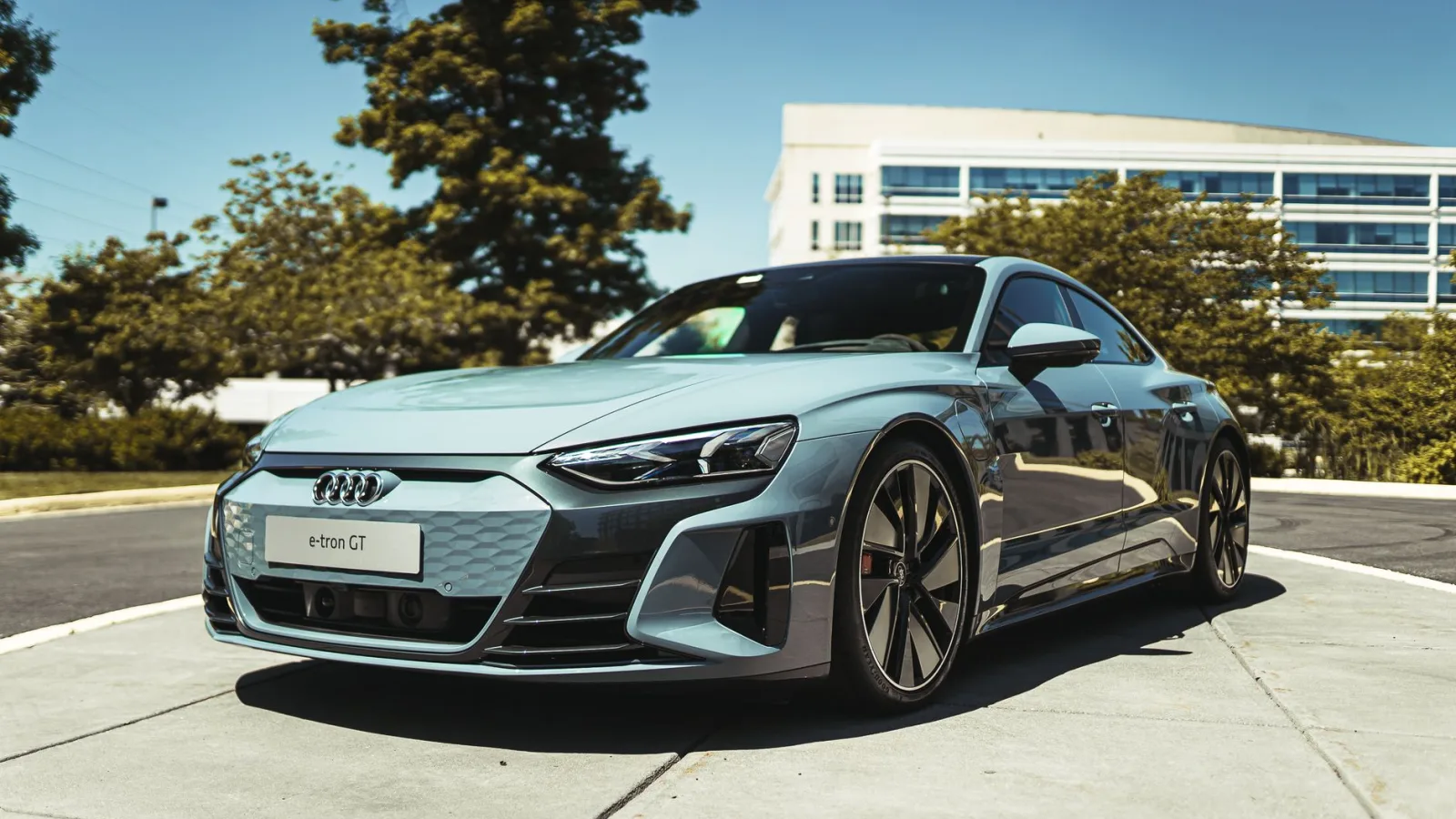 A luxurious Audi e-tron GT electric car parked in a modern urban area under clear skies.