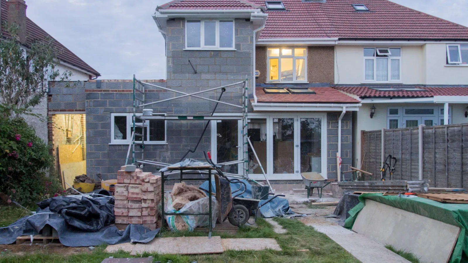 A suburban house undergoing major renovations with scaffolding and building materials.