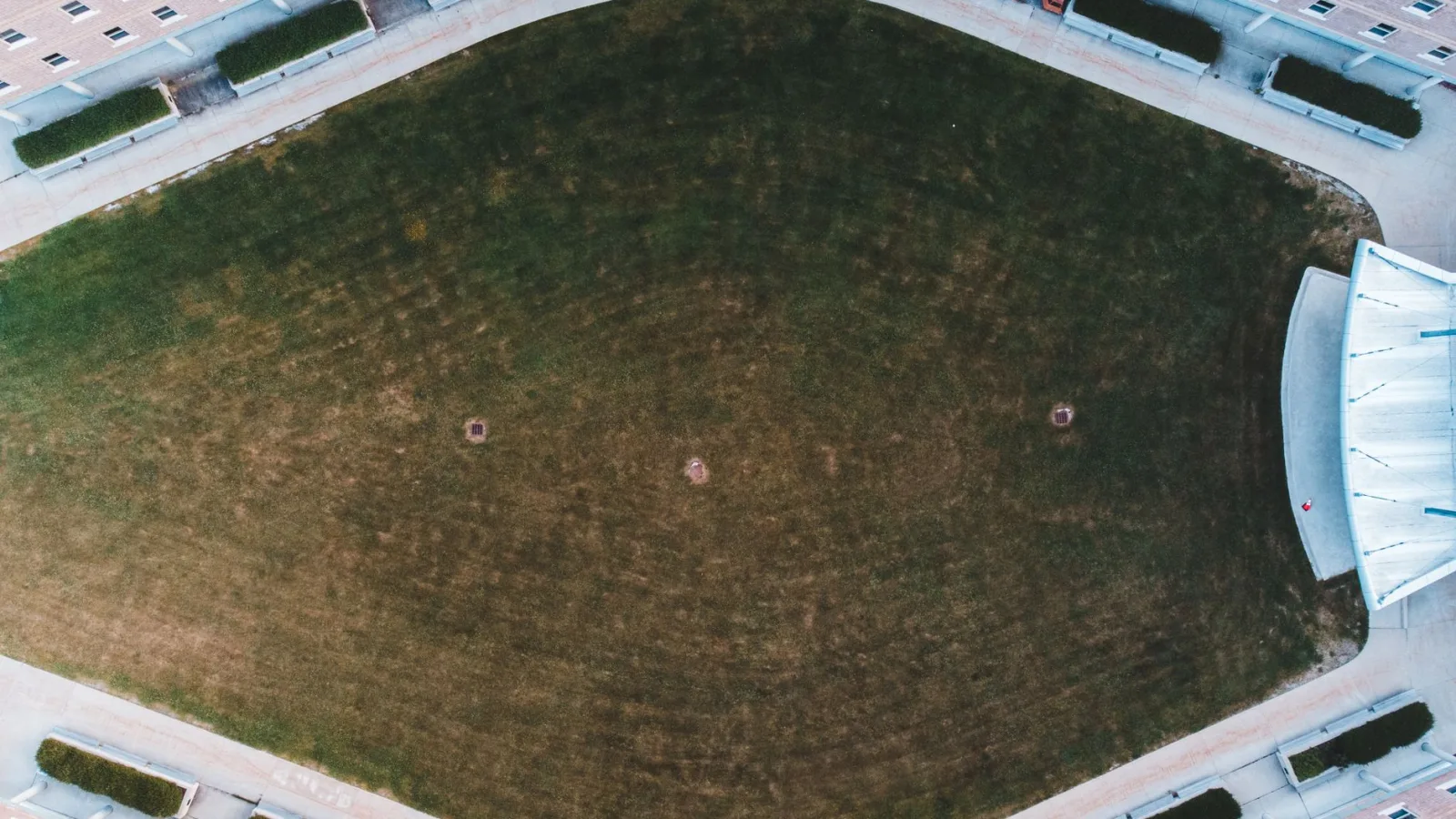 Drone shot of a symmetrical green courtyard surrounded by a building.