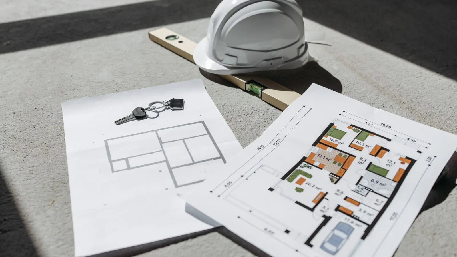 Architectural floor plans with helmet and keys on sunlit floor, perfect for real estate or construction themes.