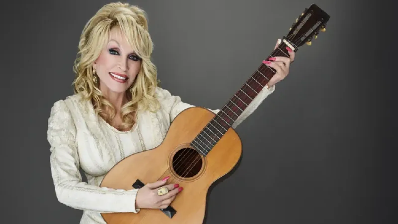Dolly Parton smiling on stage in a sequined outfit