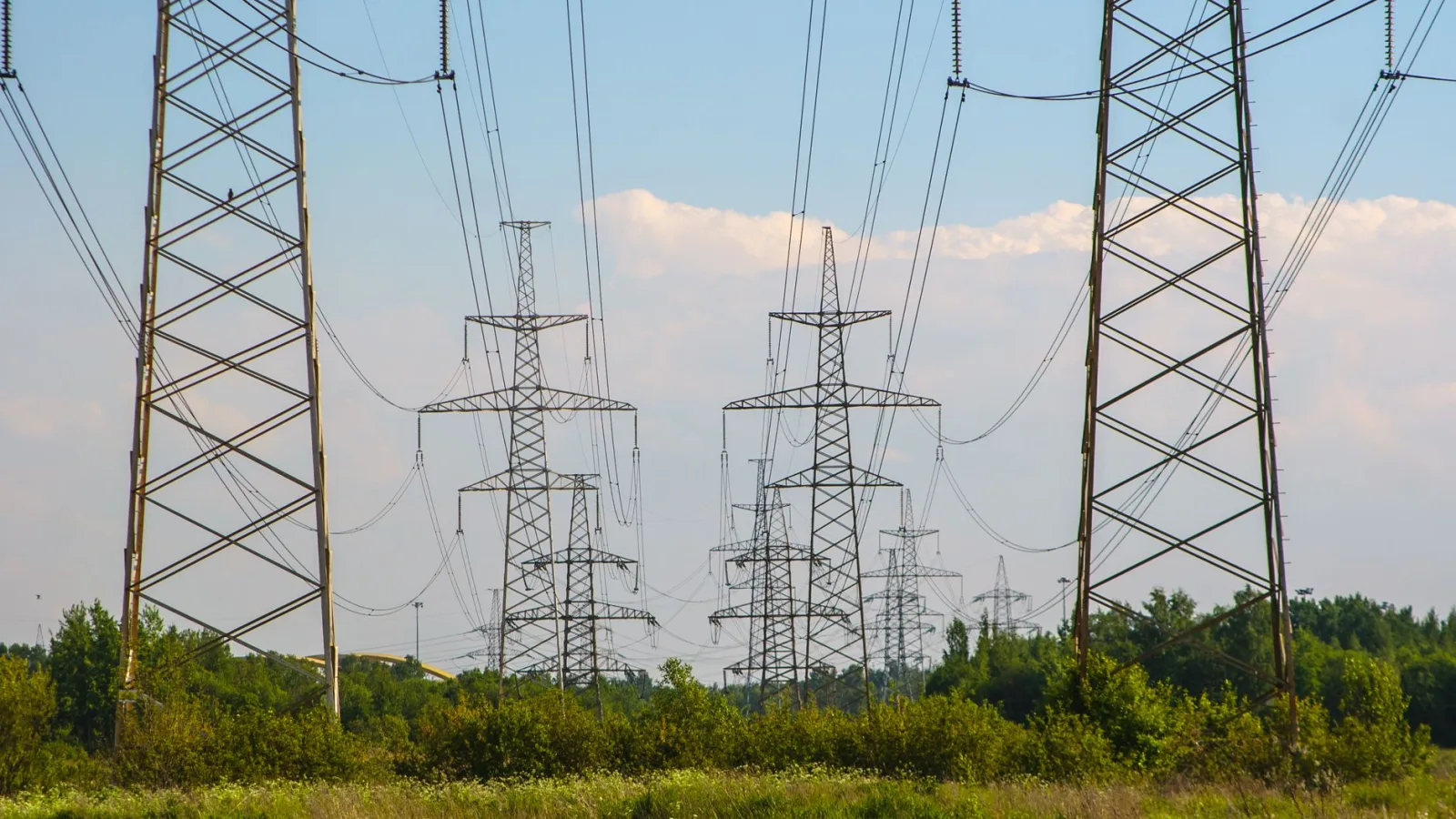 High-voltage electricity transmission towers against a cloudy sky