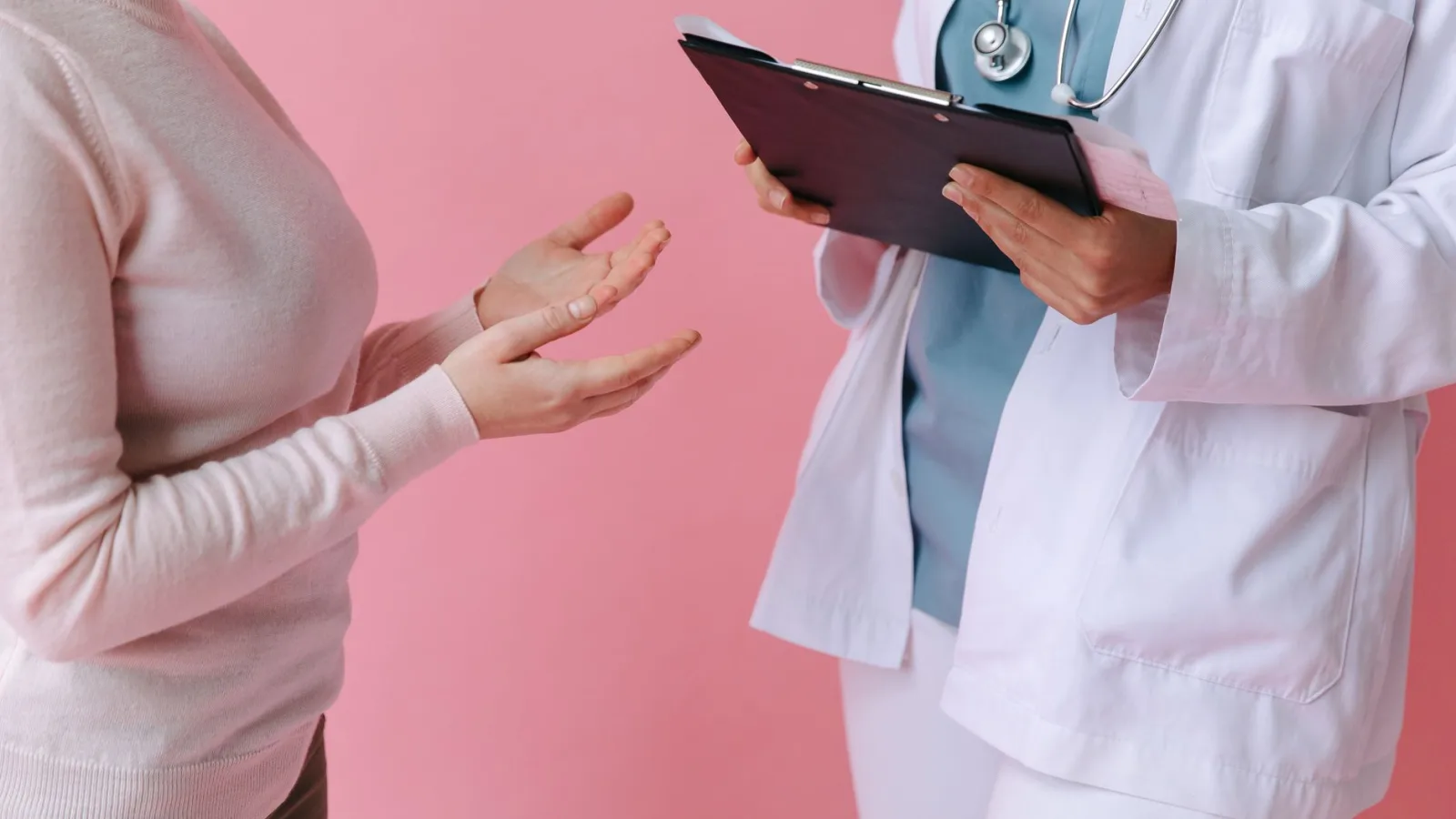 Close-up of a patient consulting a doctor with a clipboard in a medical setting.