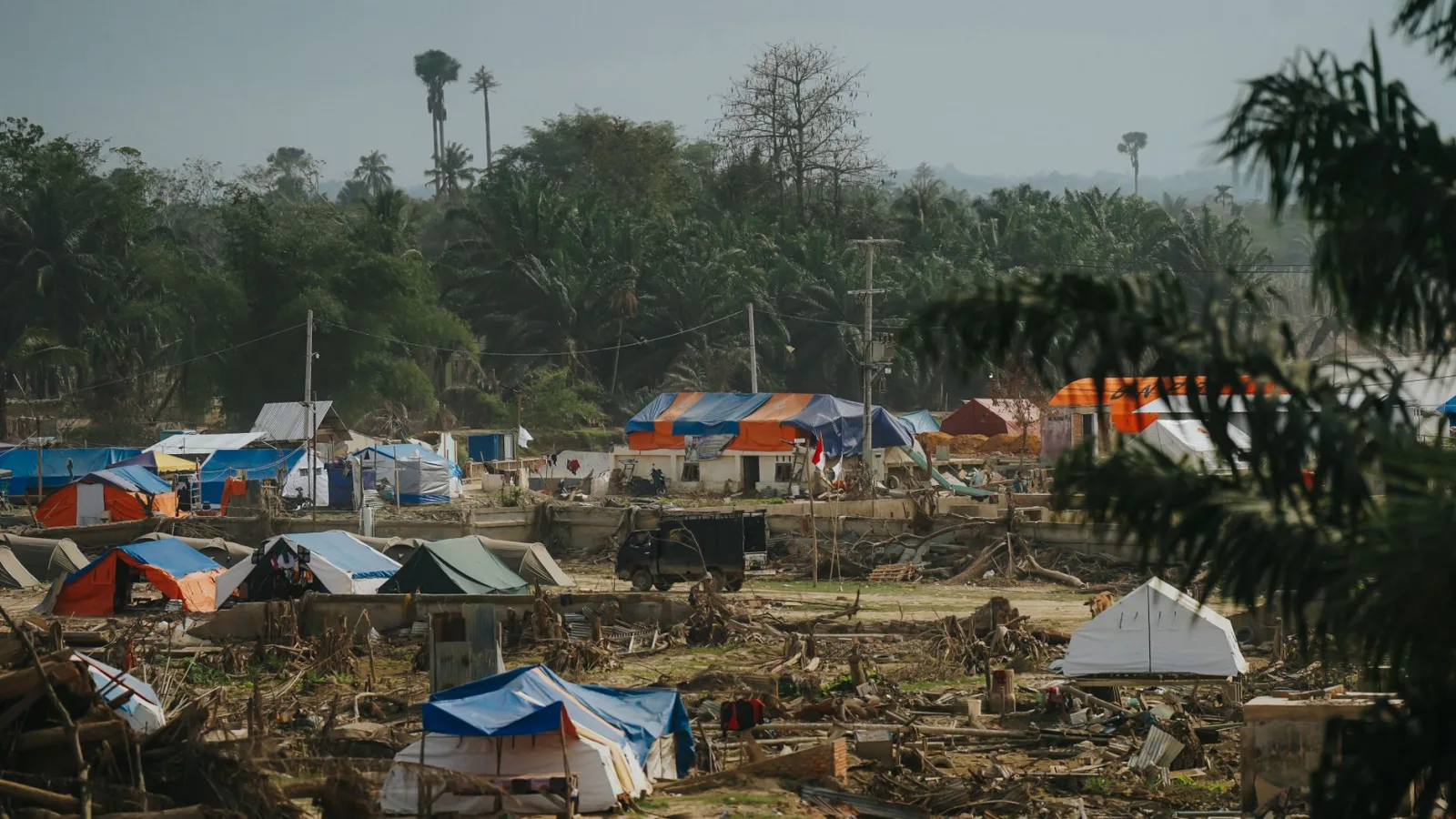 Temporary shelters in a disaster relief camp nestled in lush greenery in Aceh, Indonesia.