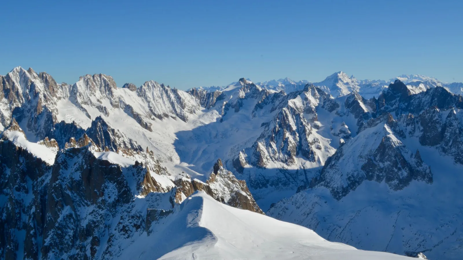A stunning view of Chamonix mountains covered in snow, under a clear blue sky.