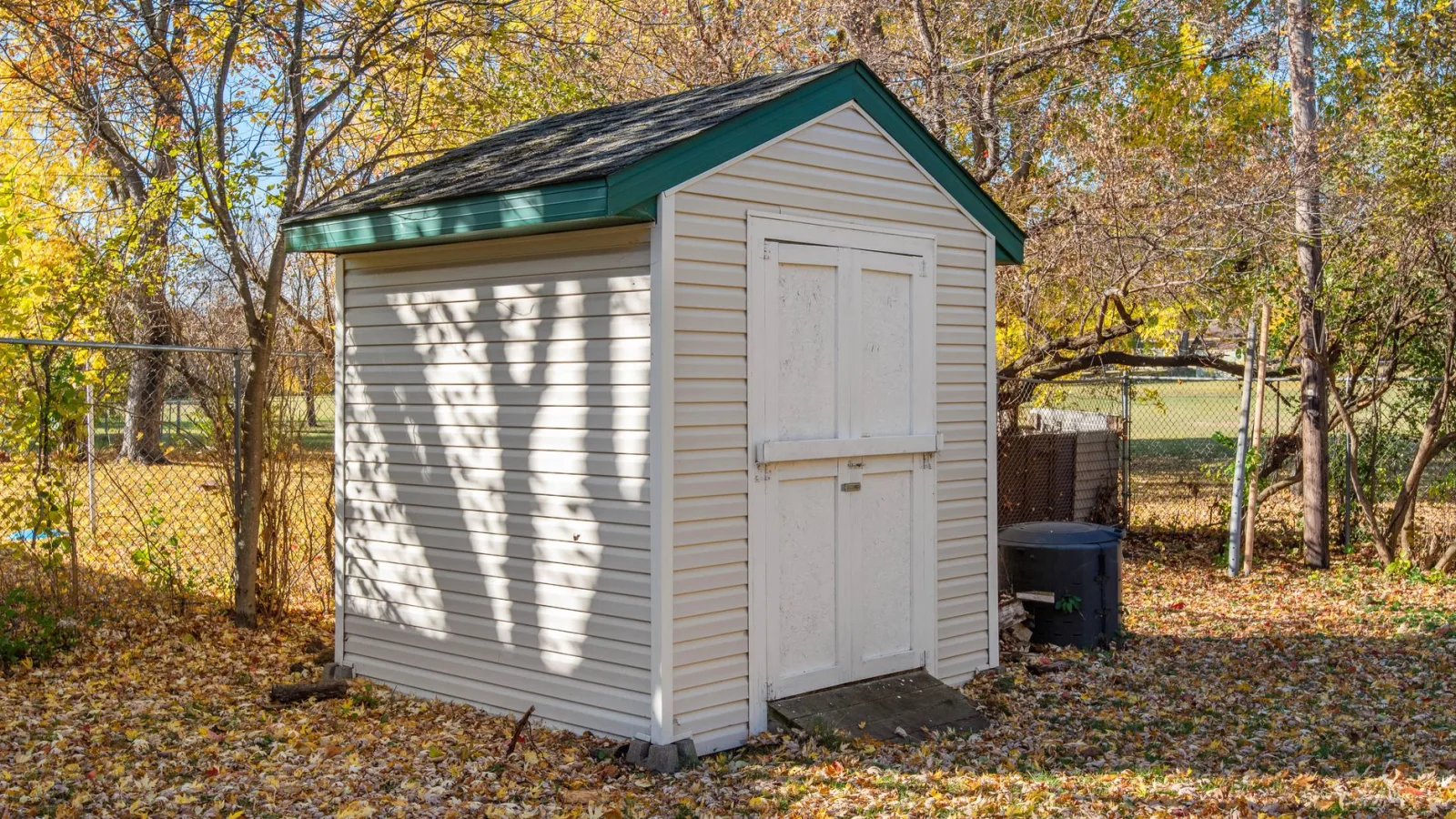 A quaint backyard shed surrounded by autumn foliage, ideal for storage solutions.
