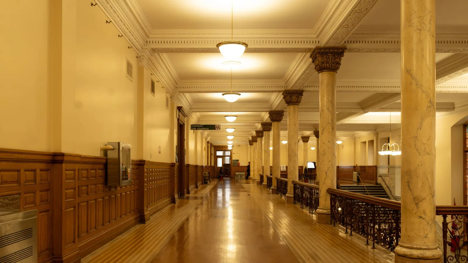Spacious corridor with elegant marble columns and vintage lighting in a historic building.