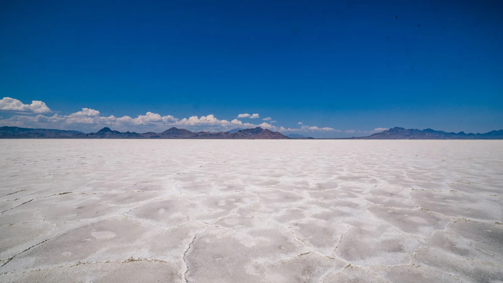 Vast Bonneville Salt Flats with distant mountains under blue sky.