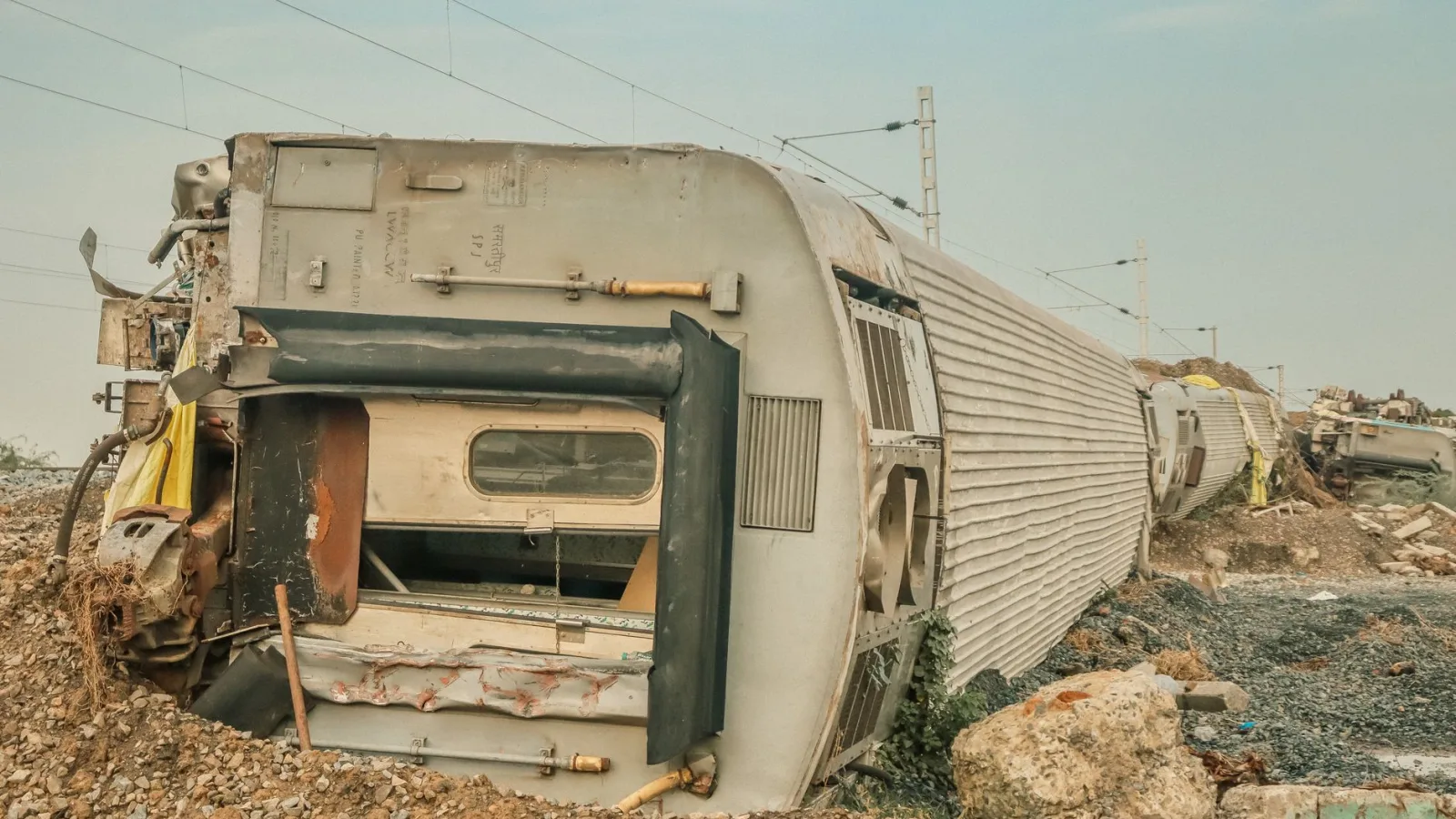 A derailed train lies overturned on a barren track, showcasing a scene of destruction.
