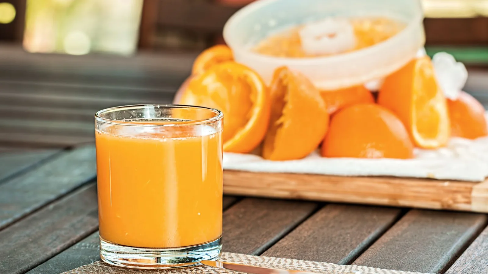 Glass of fresh orange juice with sliced oranges on wooden table, perfect for breakfast and healthy living.