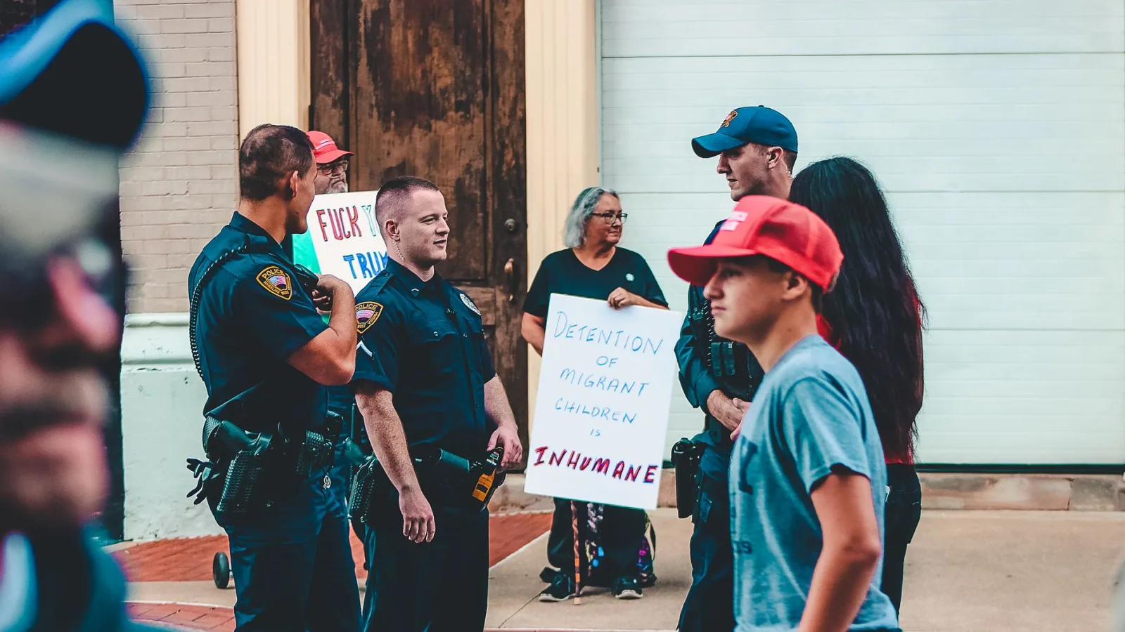 Street protest in Wheeling, WV highlighting immigration issues with signs and police presence.