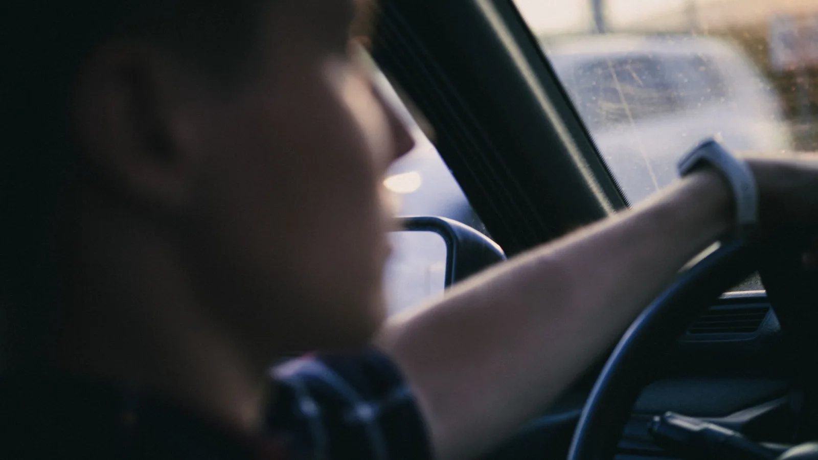 A close-up shot of a driver holding a steering wheel, focusing on the hand and interior details.