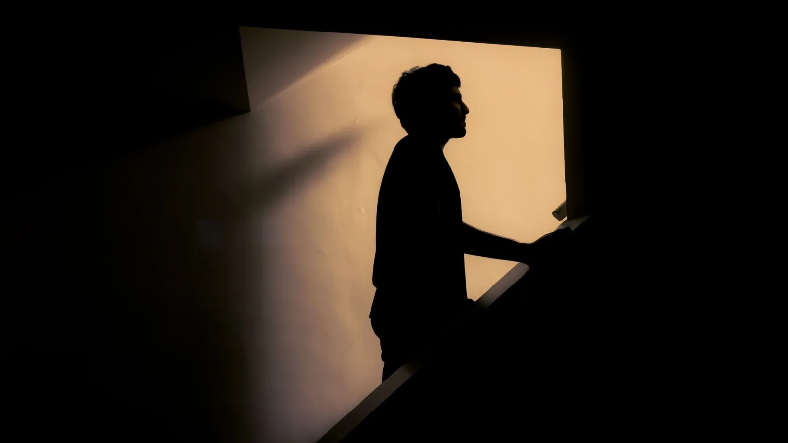 Artistic silhouette of a man on stairs with dramatic lighting.