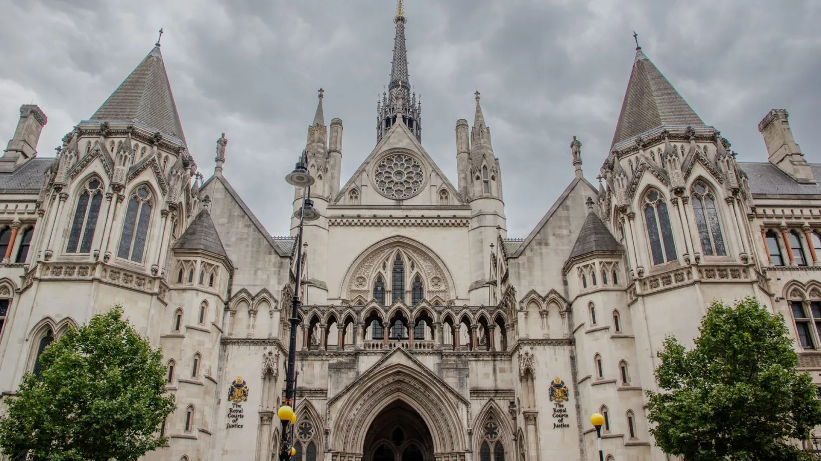Exterior of the Royal Courts of Justice in London with cloudy skies.