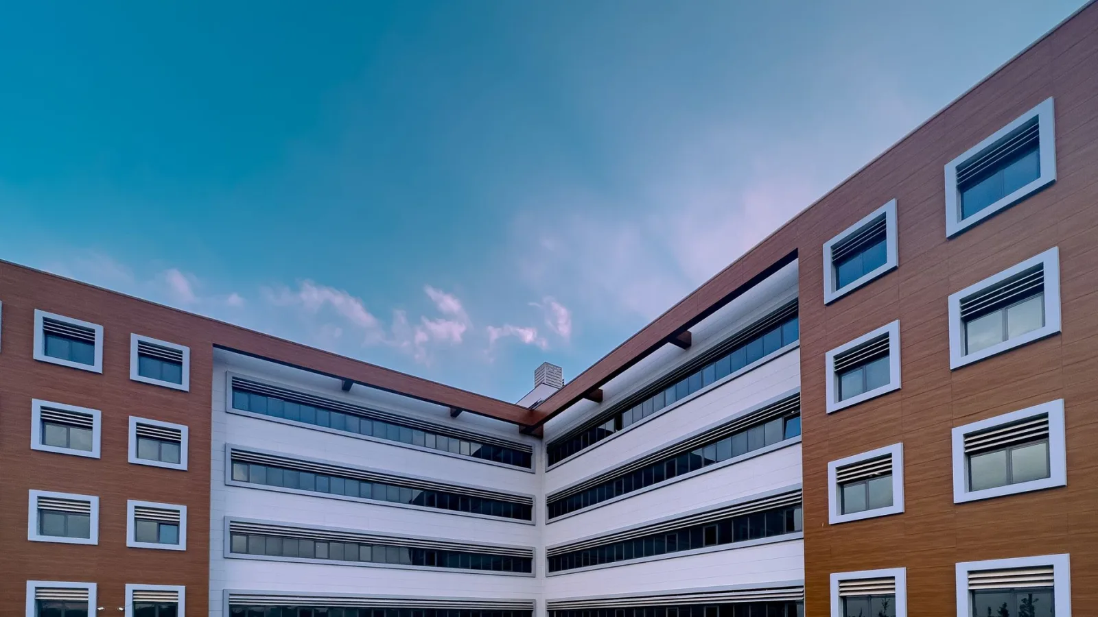 A contemporary office building with glass windows under a clear blue sky.