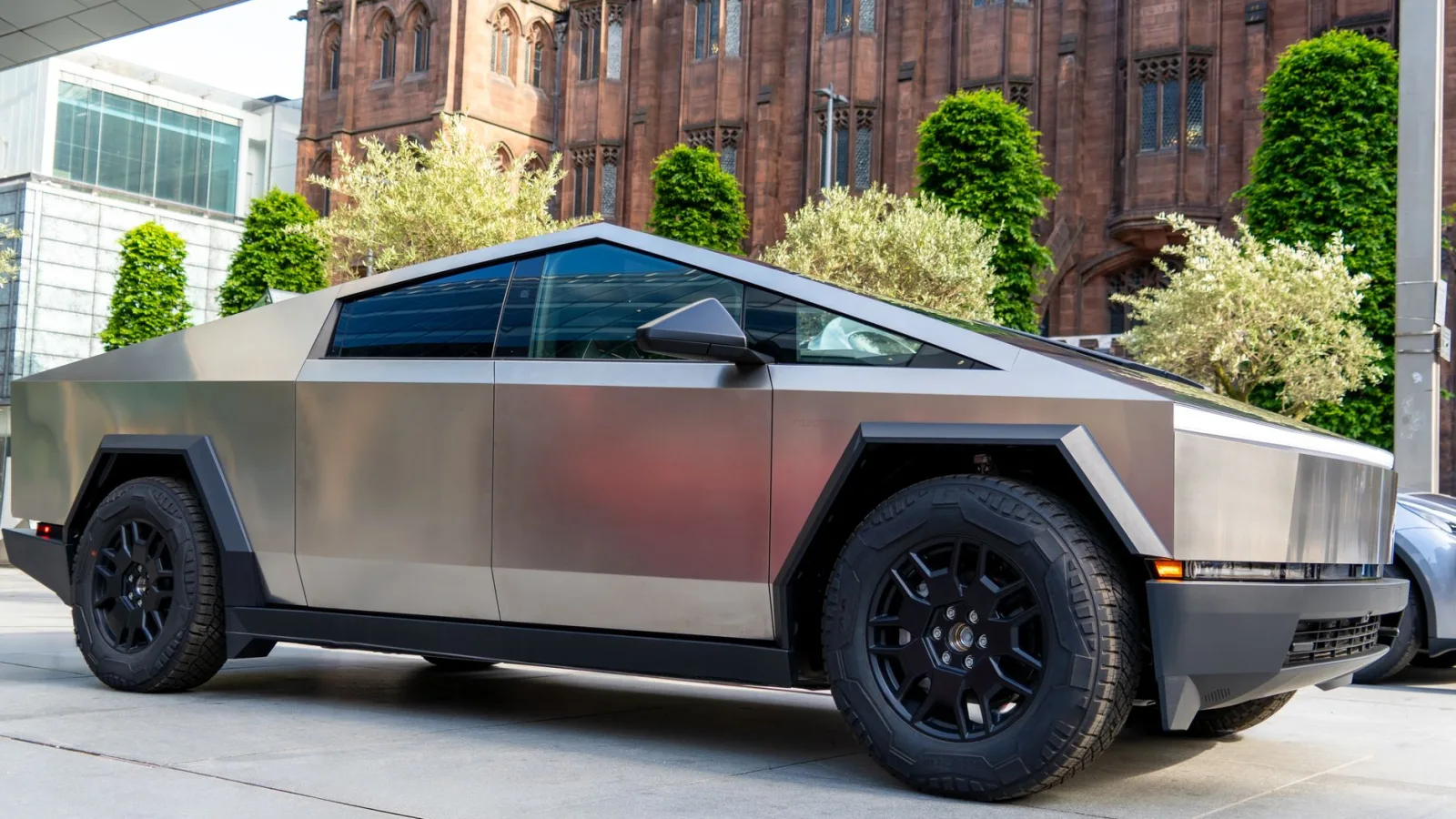 A modern electric truck parked in front of historic Manchester architecture.