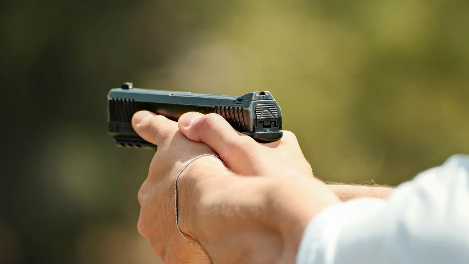 Detailed shot of a person holding a pistol outdoors, focused on safety and precision.