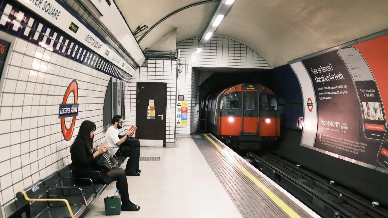 Passengers wait as a train arrives at Leicester Square Tube station in London.