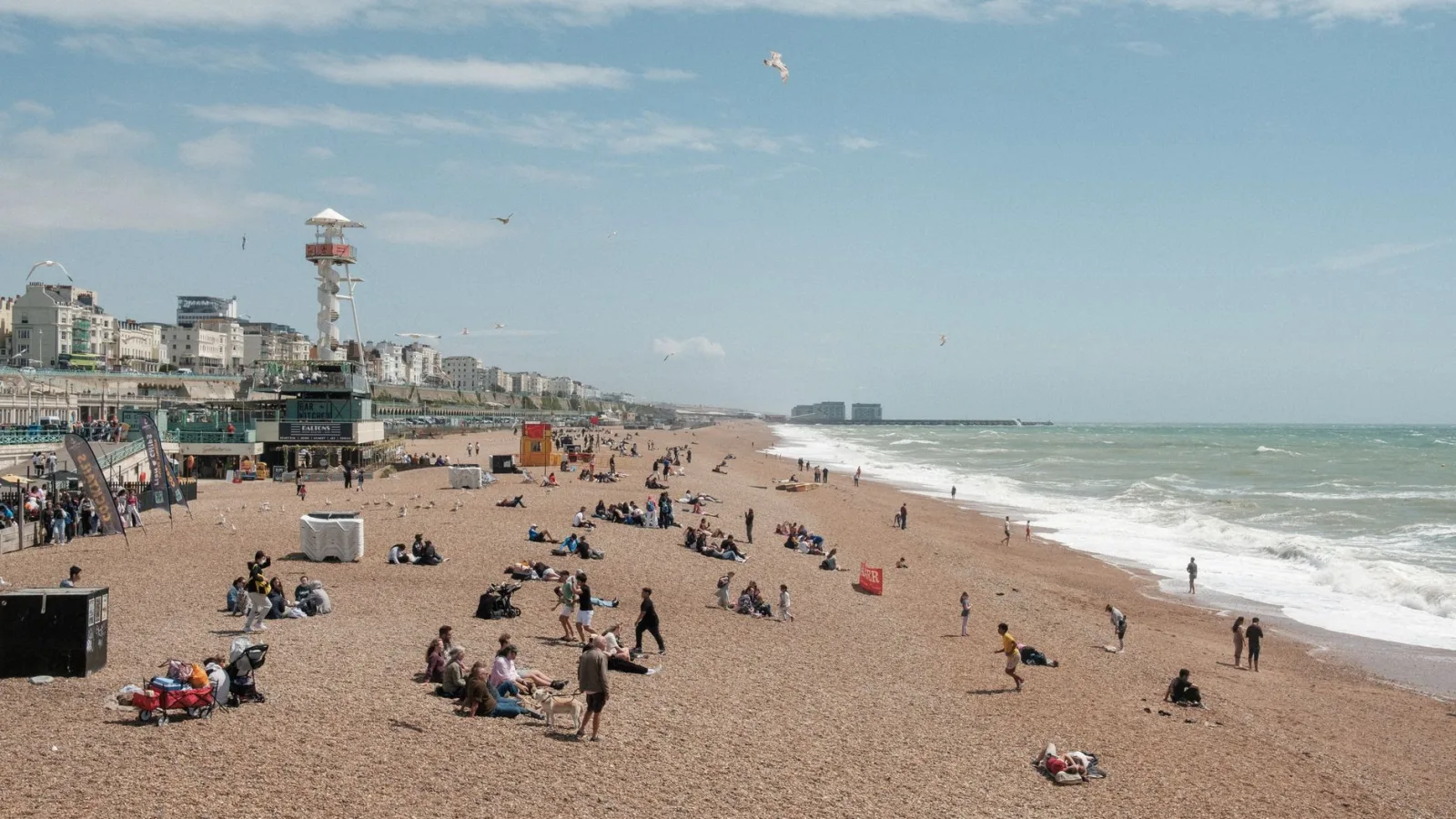 A lively scene at Brighton Beach with people enjoying a sunny day by the sea.